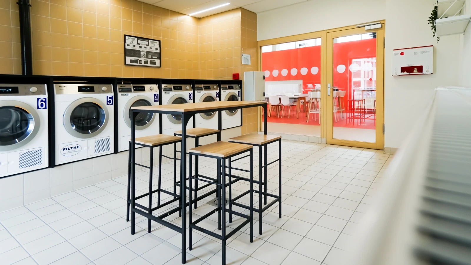 Laverie collective avec lave-linge, table haute et espace de pliage