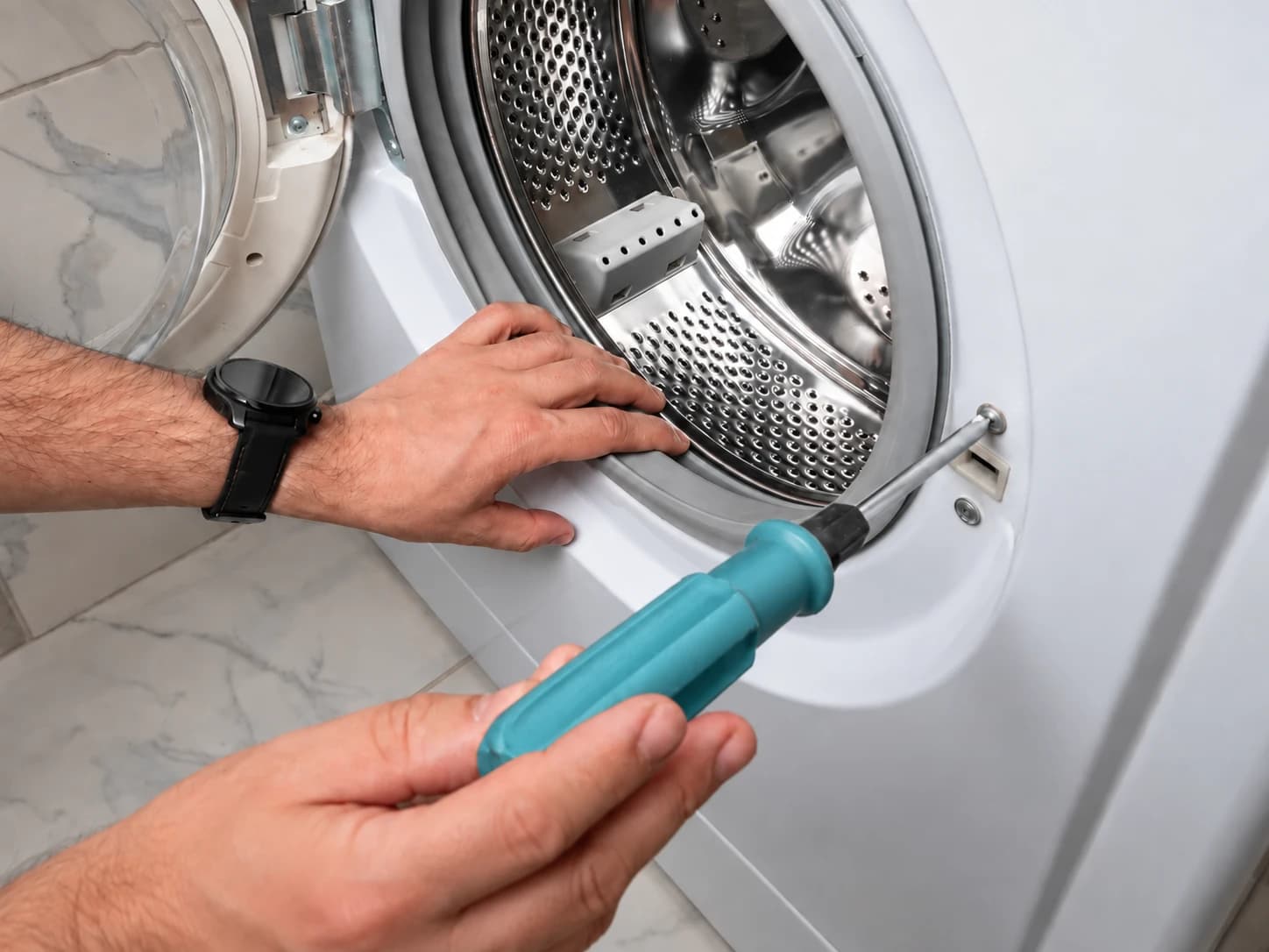 Intervention au tournevis près du verrou d’un hublot de lave-linge